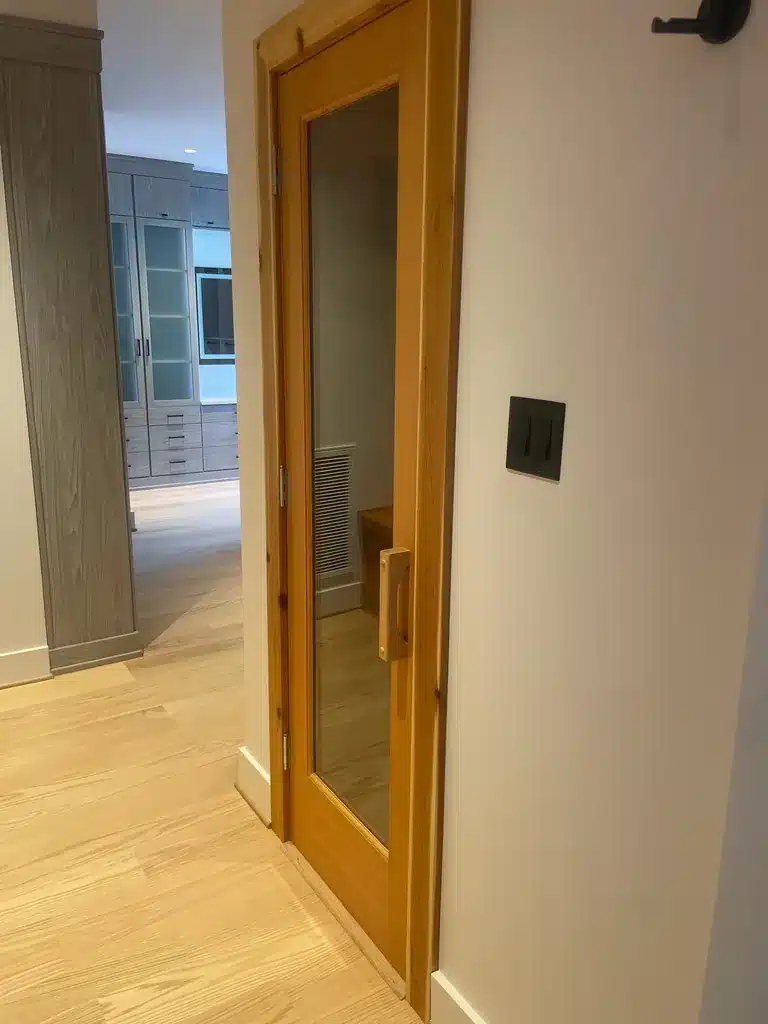 Glazed sauna door viewed from the hallway beside the primary bathroom