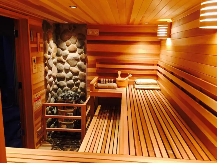 Finished Finlandia FPC precut sauna interior with cedar benches and a stone-accent heater