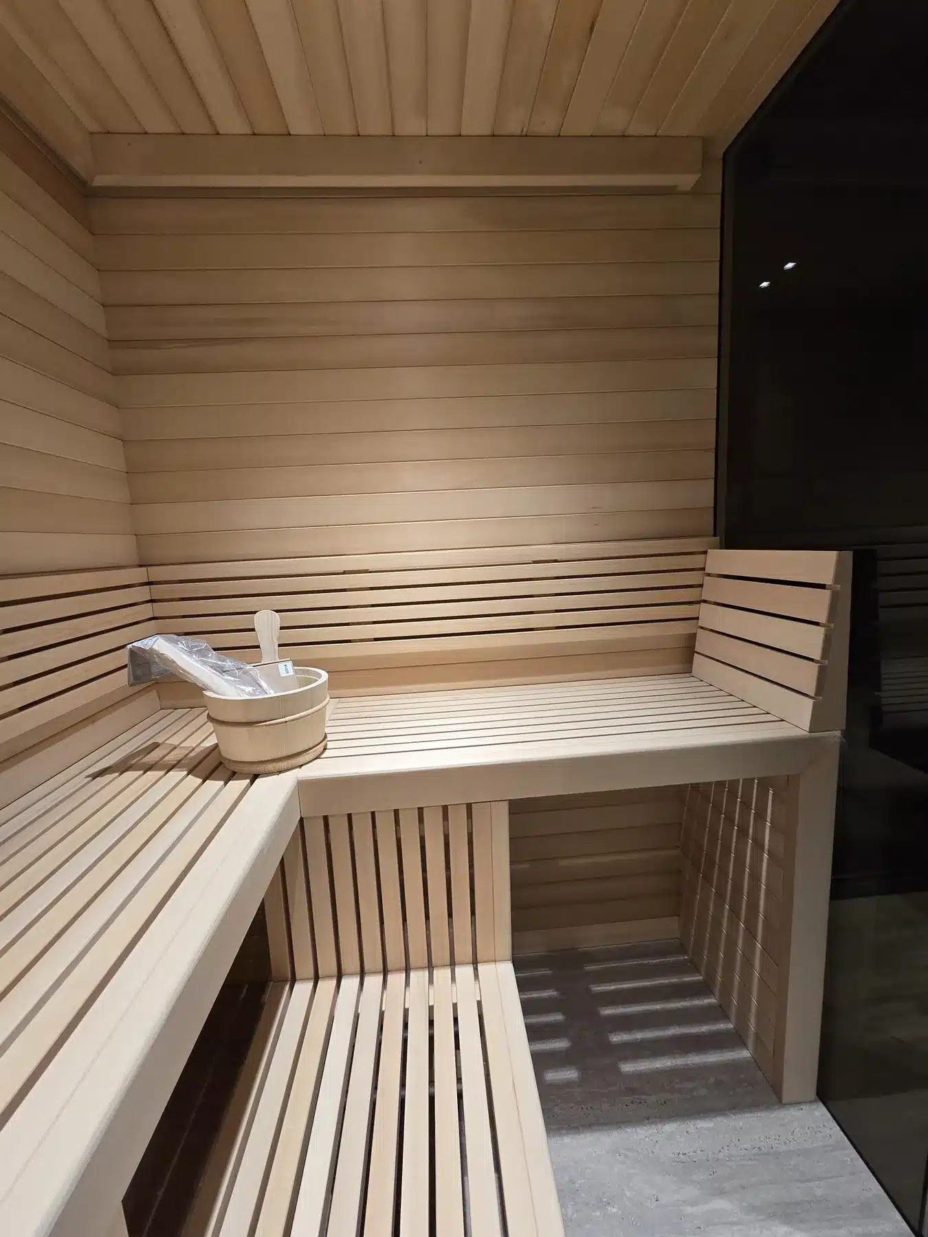 Alaska Yellow Cedar sauna interior beside a dark glass end panel